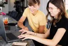 Two women discussing while looking at a laptop.