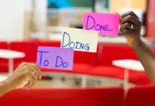 Two hands holding kanban sticky notes that say, "to do, doing, done."